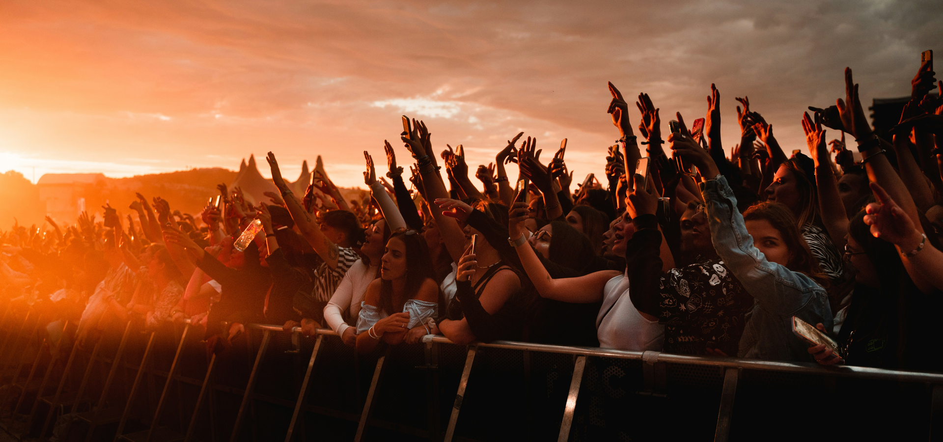 Openluchtconcert tijdens het zomerconcertseizoen met een juichend publiek voor het podium bij zonsondergang.